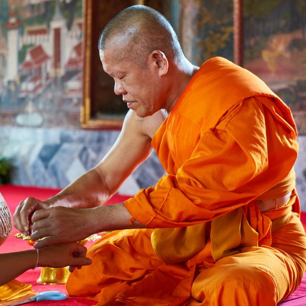 Буддийский монах завязывает верёвочку на руке