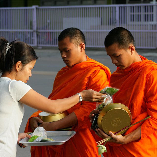 Женщина передаёт монахам еду